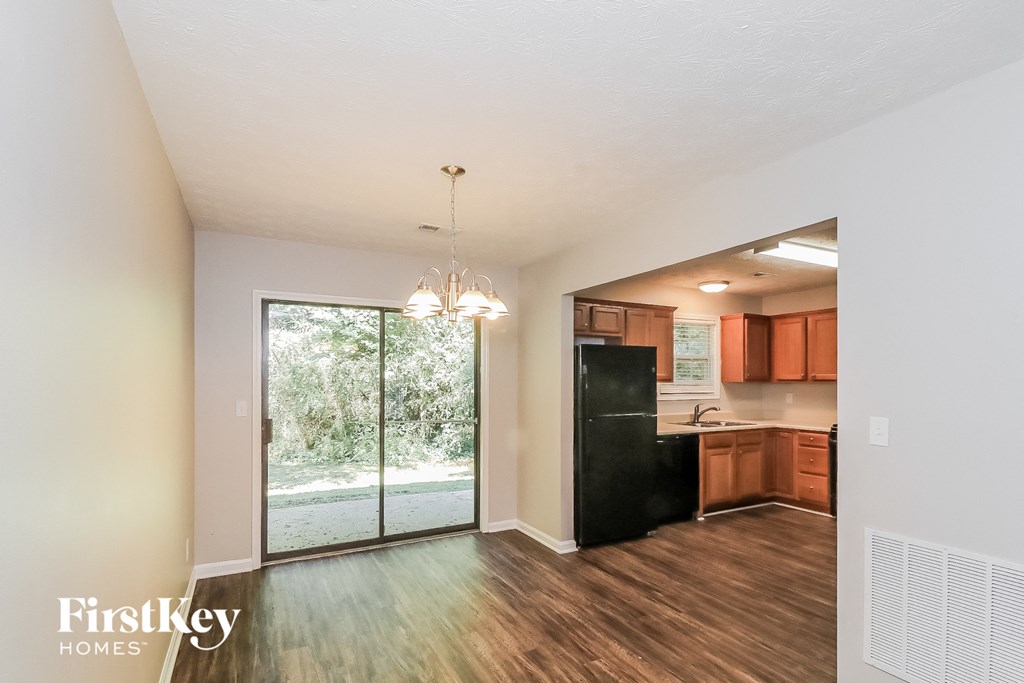 an empty living room with a kitchen and a sliding glass door