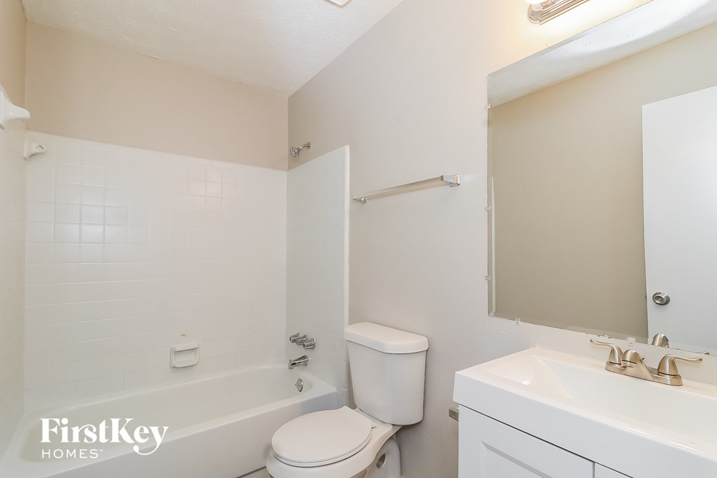 a bathroom with a toilet sink and tub and a mirror