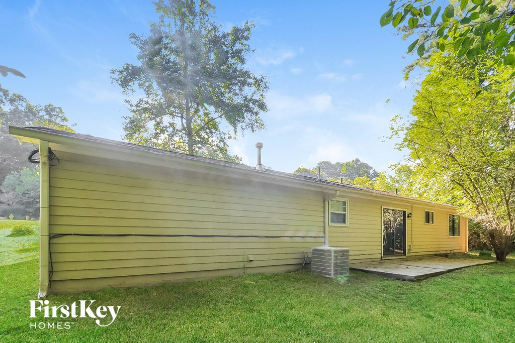 the front of a yellow house with a lawn and trees