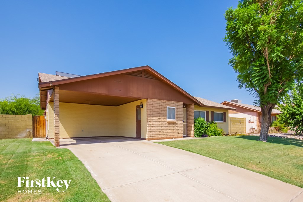 a small brick house with a driveway and a tree