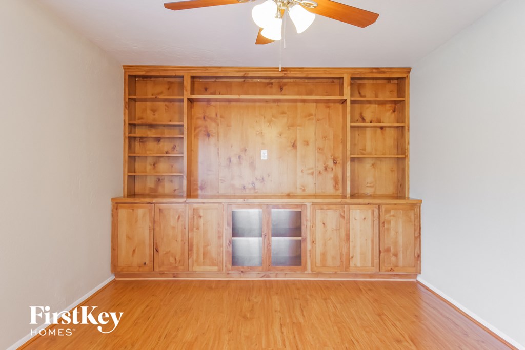 a living room with a wood floor and a bookshelf and a ceiling fan