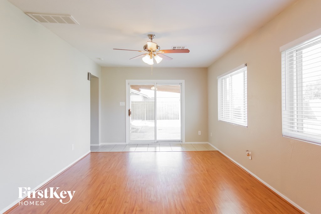 an empty living room with wood floors and a ceiling fan