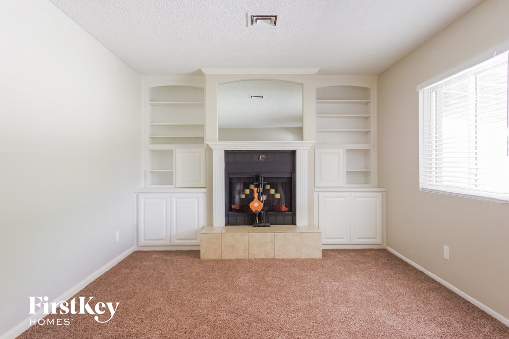 a living room with a fireplace and white shelves