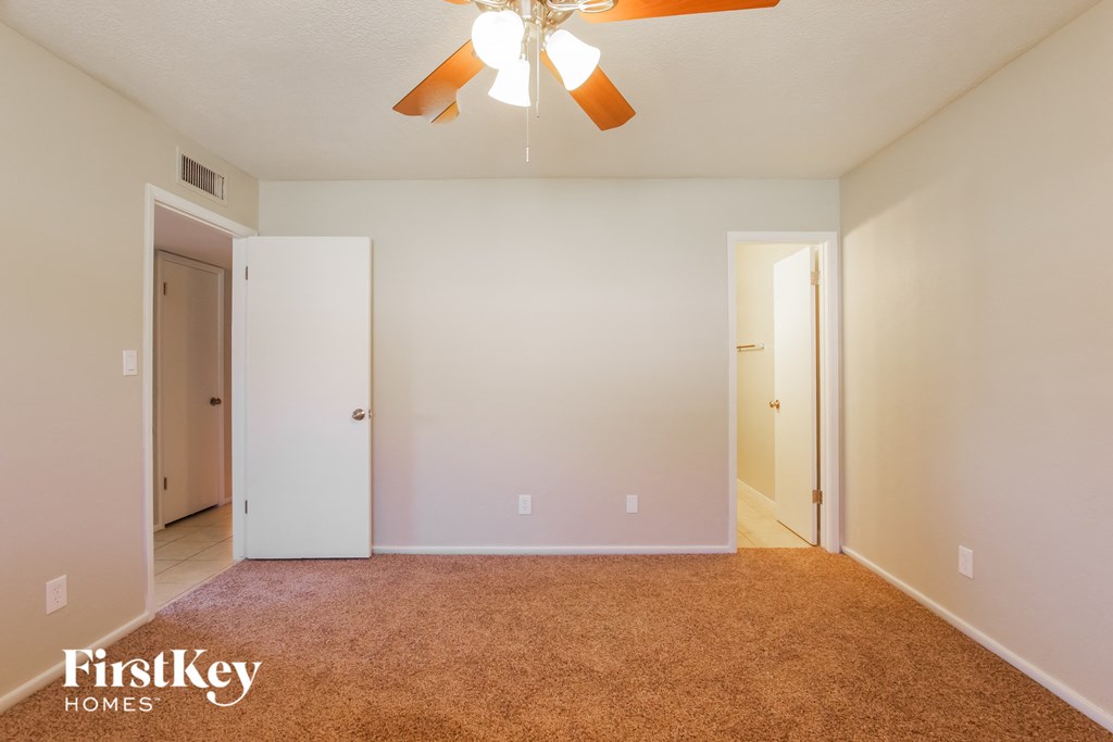 a bedroom with a carpeted floor and a ceiling fan