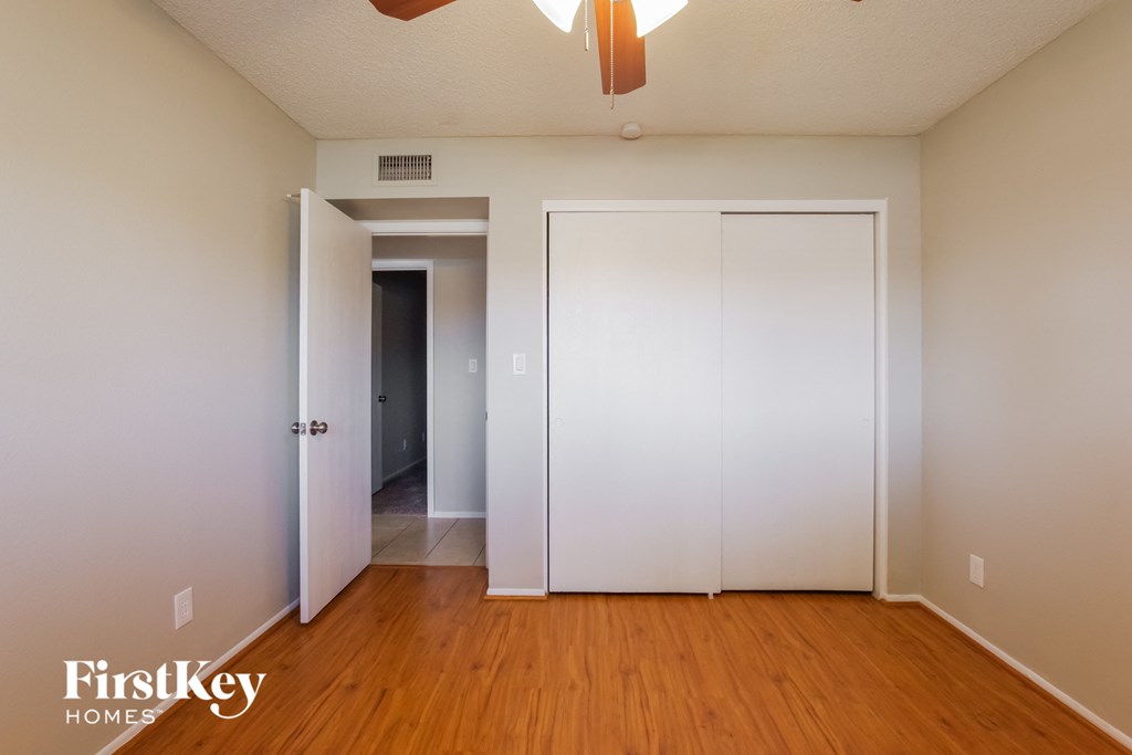 a bedroom with white walls and wood floors and a closet
