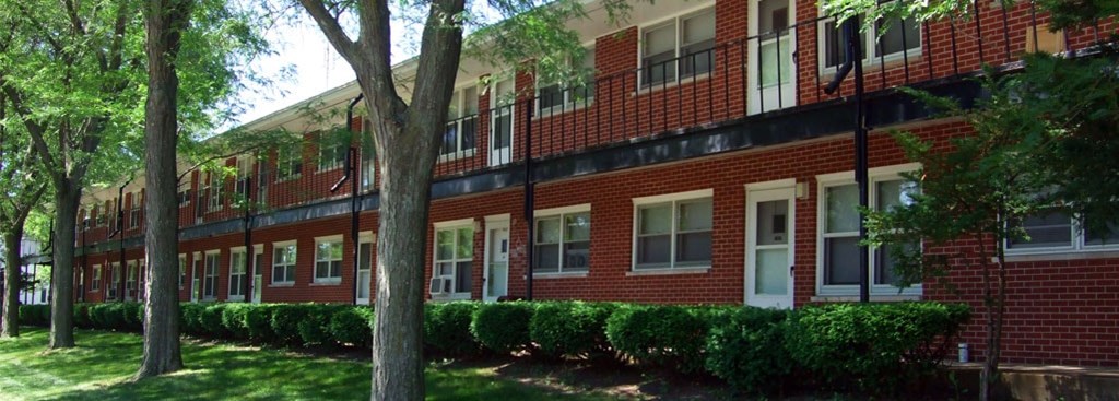 A red brick building with green bushes in front.