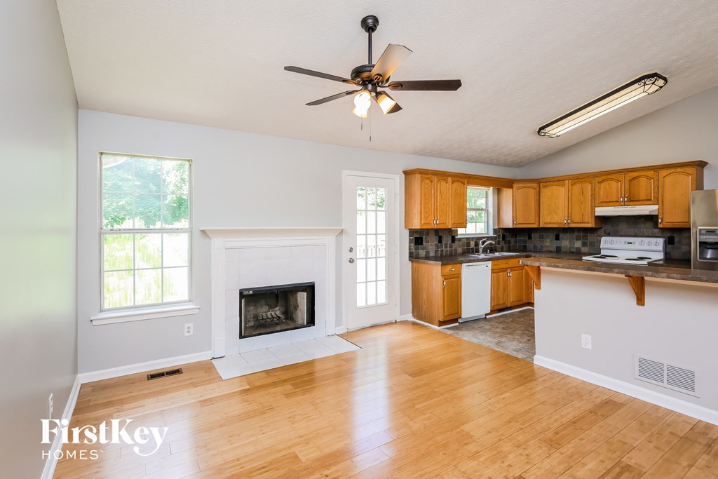 an empty living room with a ceiling fan and a fireplace