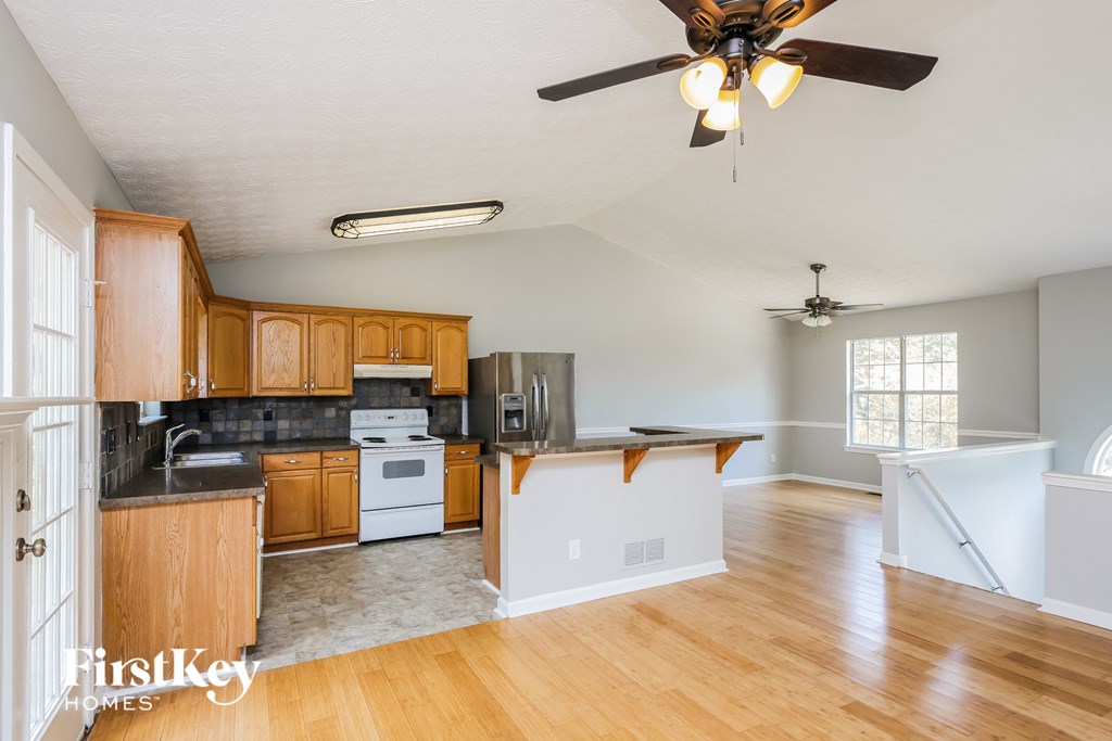 an empty kitchen with a ceiling fan and wood floors