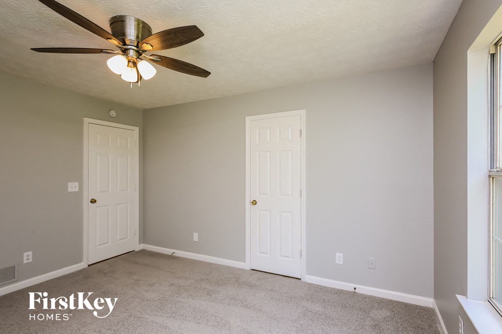 a bedroom with a ceiling fan and two doors