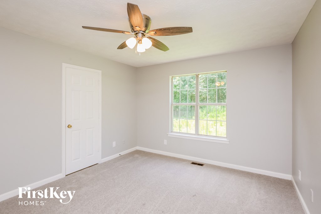 an empty room with a ceiling fan and a window