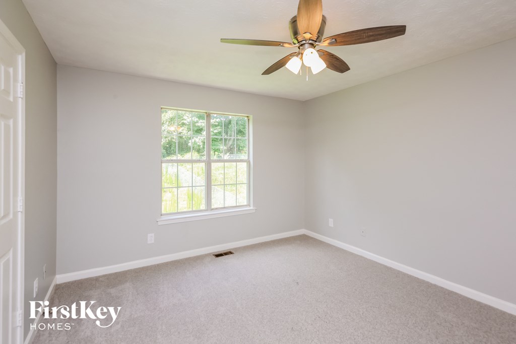 an empty room with a ceiling fan and a window