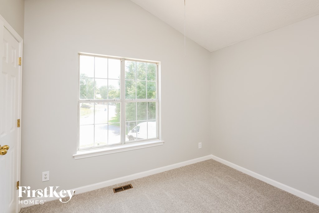 a bedroom with a large window and a carpeted floor
