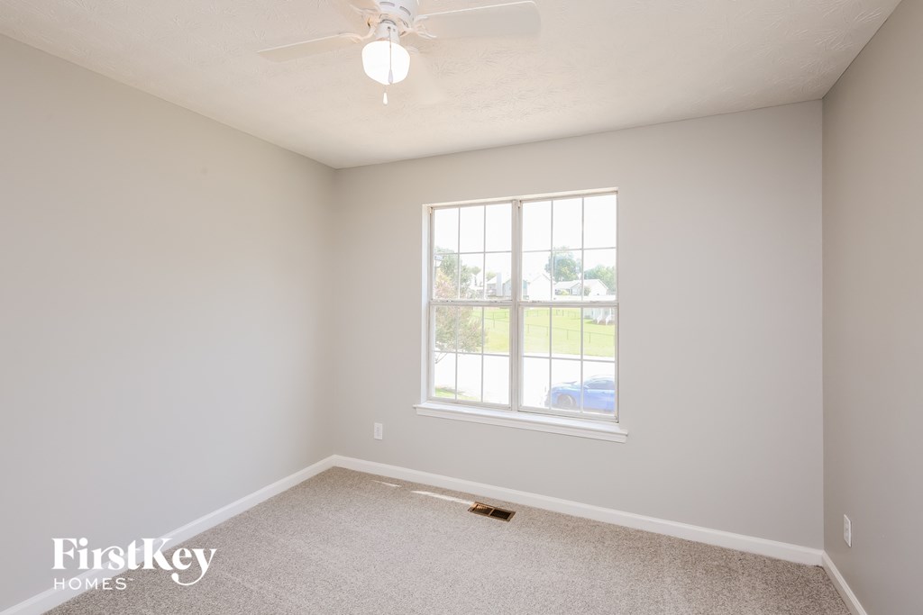 a bedroom with a large window and a ceiling fan