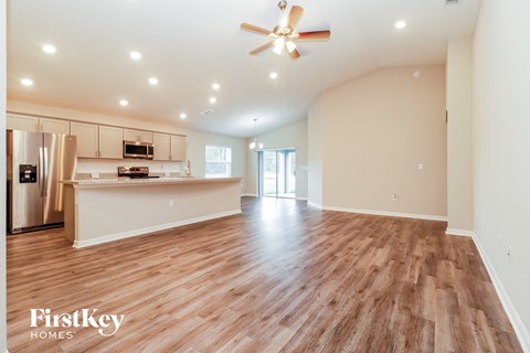 a spacious living room with a kitchen and a ceiling fan
