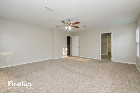 a spacious living room with carpet and a ceiling fan