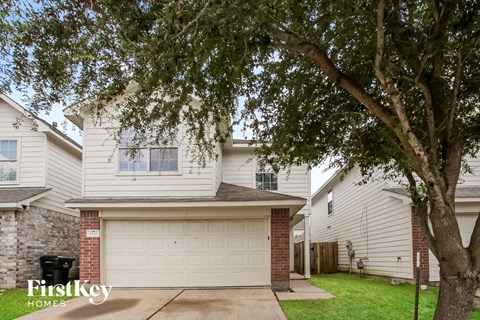 a white house with a white garage door and a tree