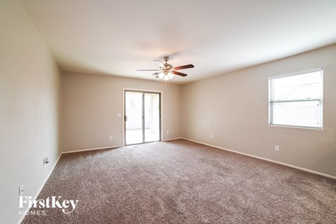 A spacious room with a ceiling fan and carpeted floor.