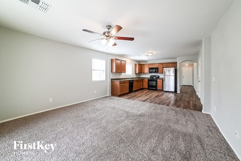 A spacious room with a carpeted floor and a ceiling fan.