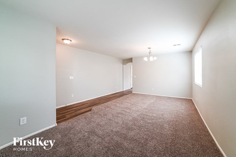 A carpeted room with a wooden floor and a window on the right side.