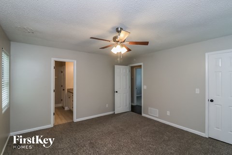 a living room with a ceiling fan and a carpet