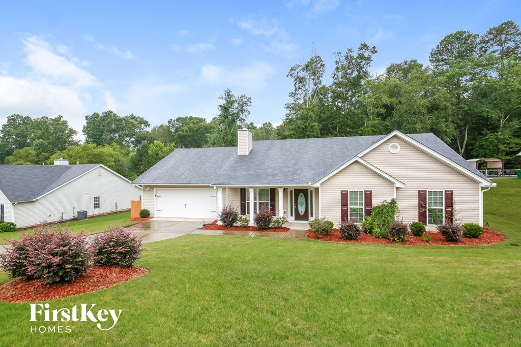 a white house with red doors and a yard with a green lawn and trees