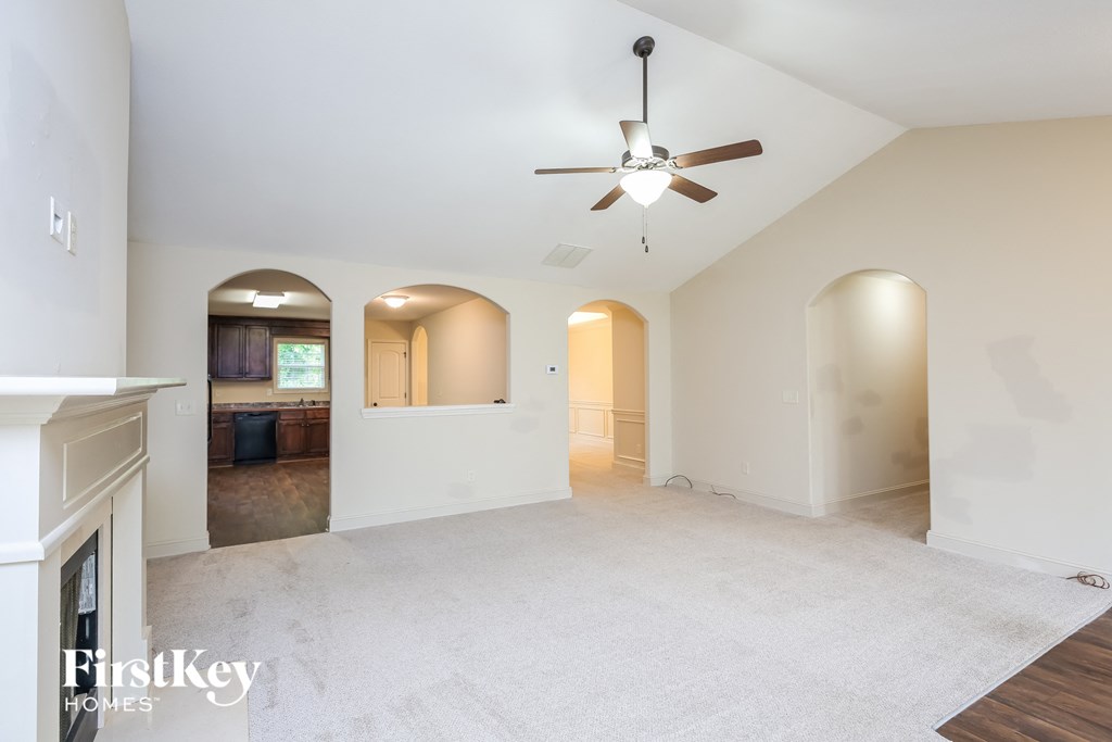 an empty living room and kitchen with a ceiling fan