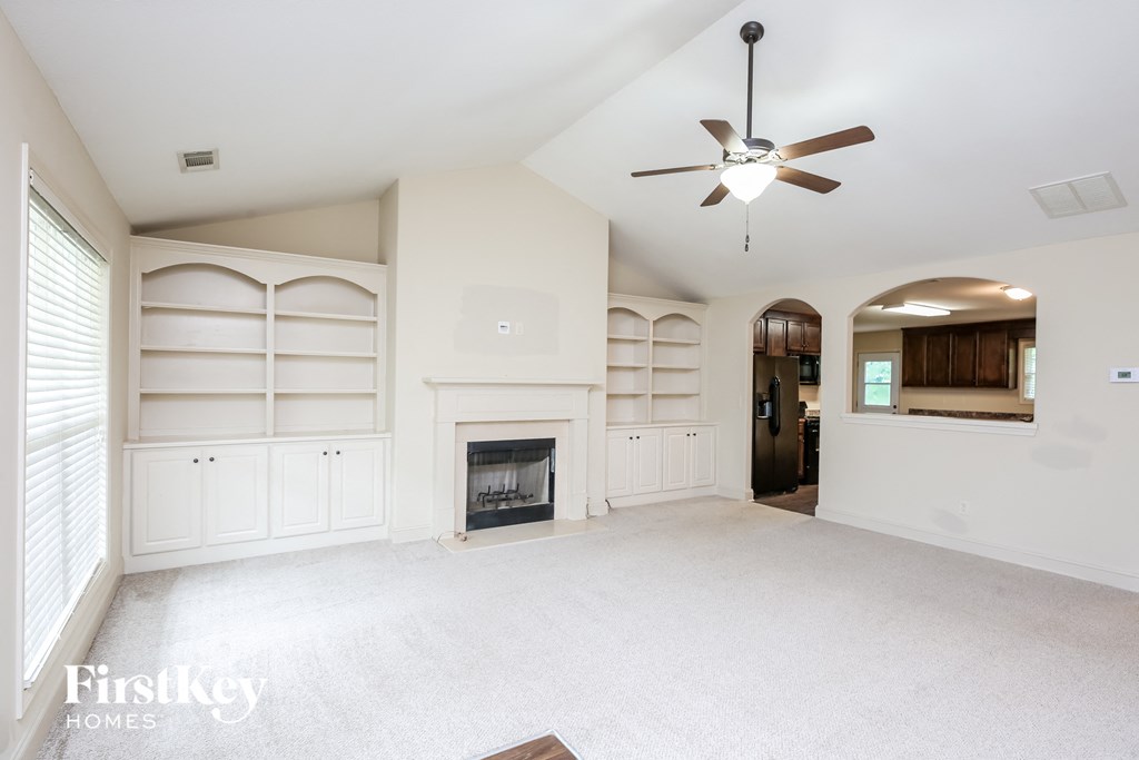 an empty living room with a fireplace and white shelves
