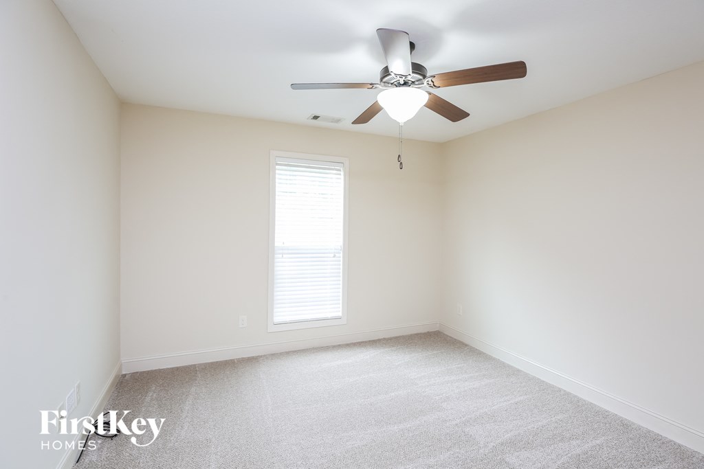 an empty room with a ceiling fan and a window