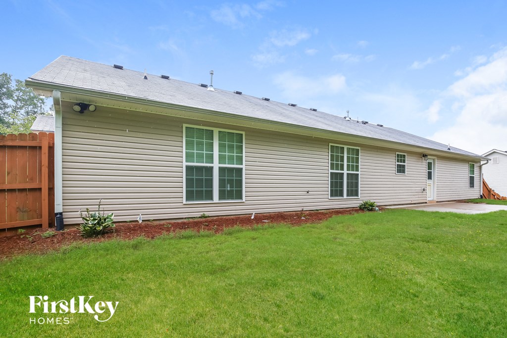 the front of a house with a lawn and a wooden fence