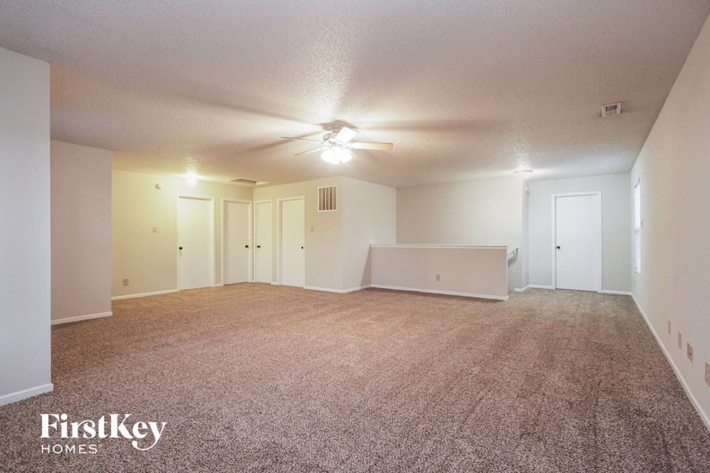 an empty living room with carpet and a ceiling fan