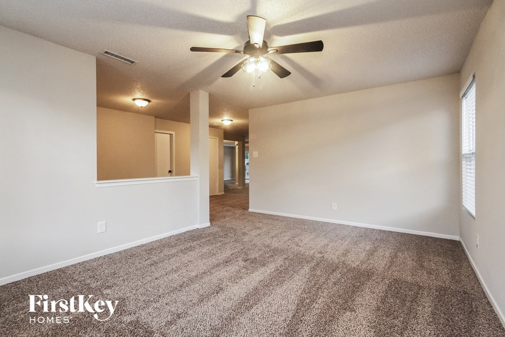 an empty living room with carpet and a ceiling fan