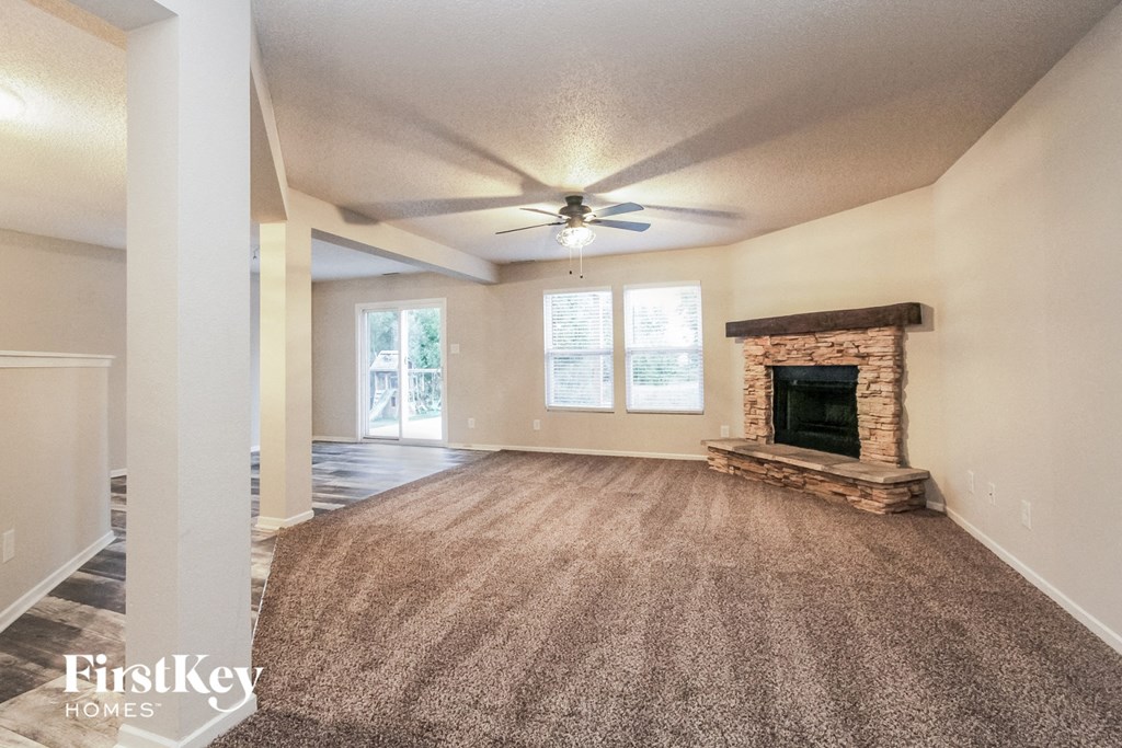 an empty living room with a ceiling fan and a fireplace