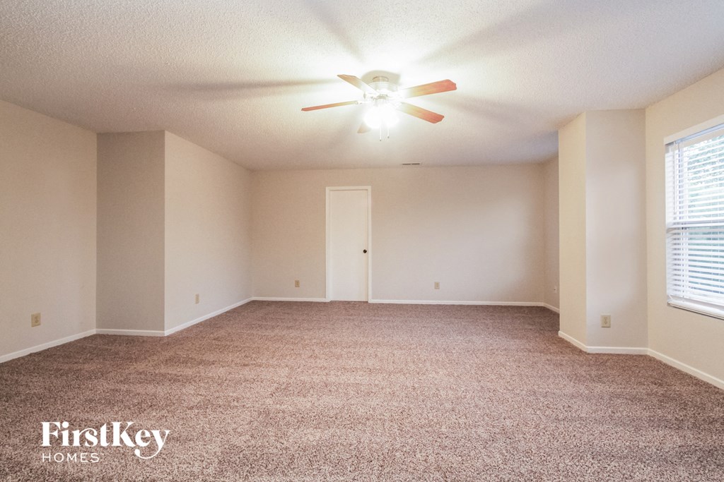 the spacious living room with carpeting and a ceiling fan