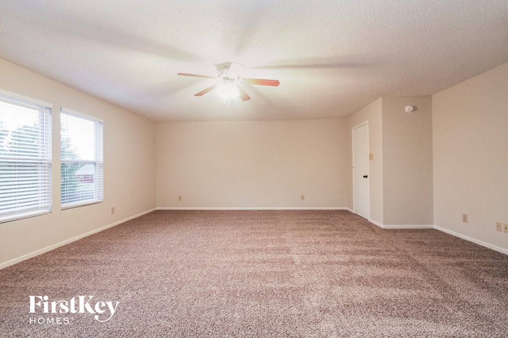 the spacious living room with carpeting and a ceiling fan