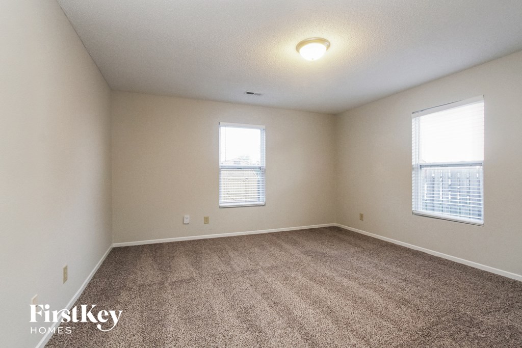 a bedroom with carpet and two windows