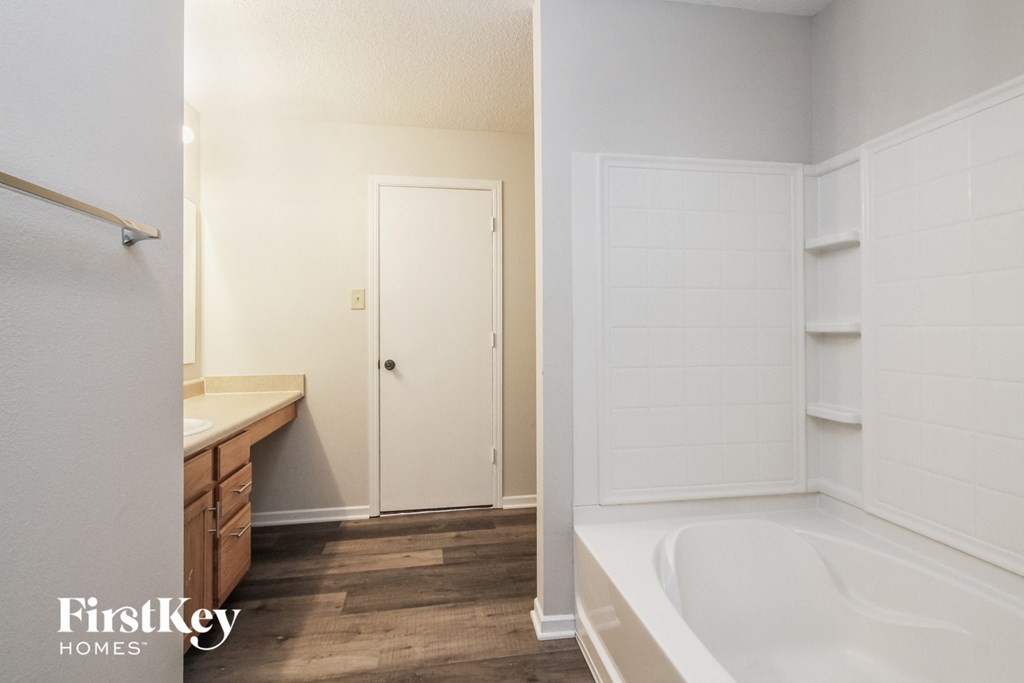 a white bathroom with a tub and a sink and a mirror