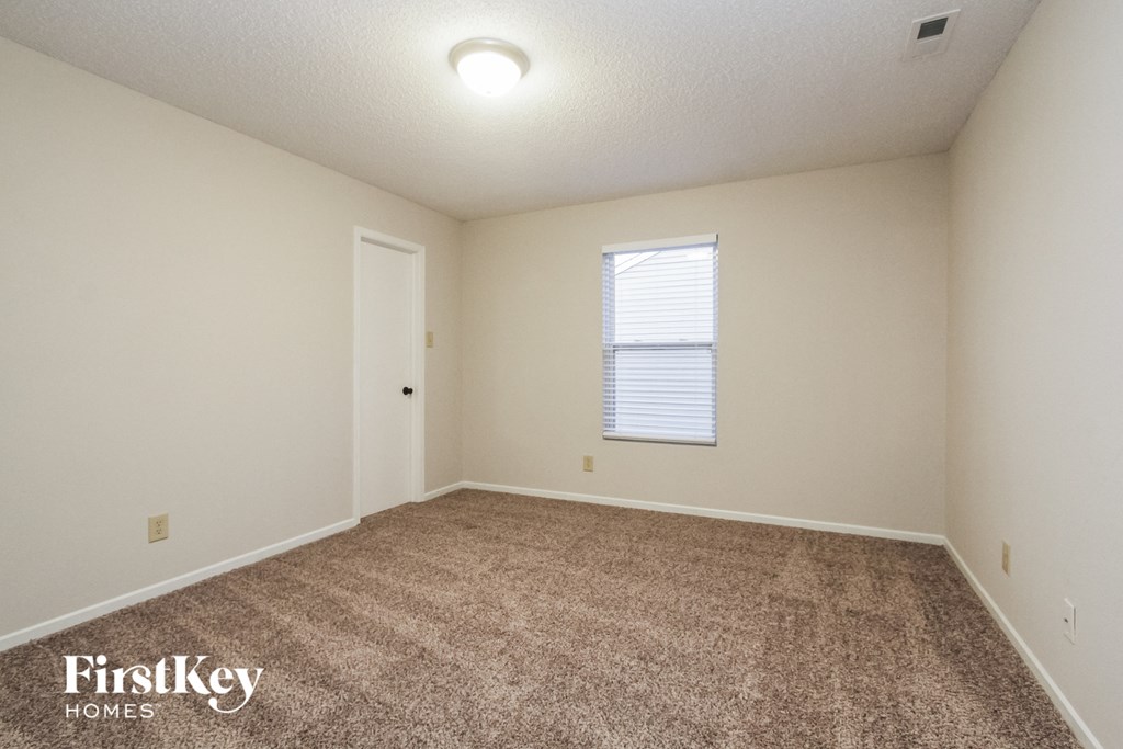 a spacious living room with carpet and a window