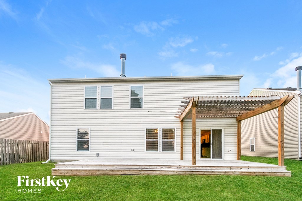 the exterior of a white house with a wooden deck and awning