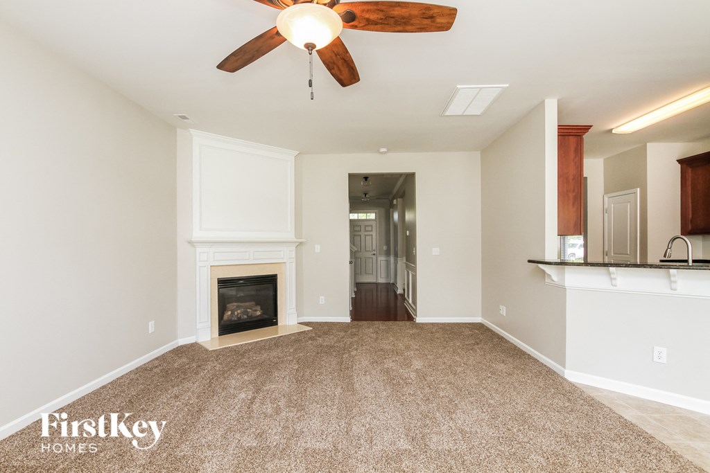 an empty living room with a fireplace and a ceiling fan