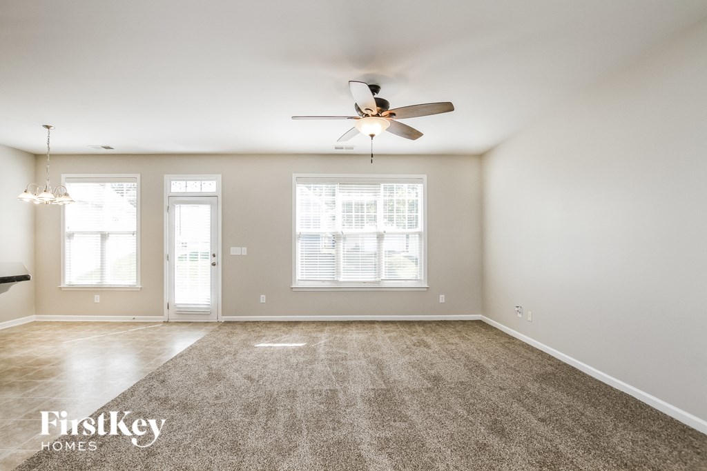 an empty living room with a ceiling fan and window