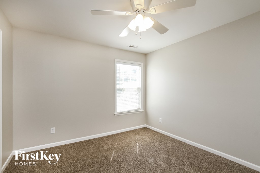 an empty room with a ceiling fan and a window