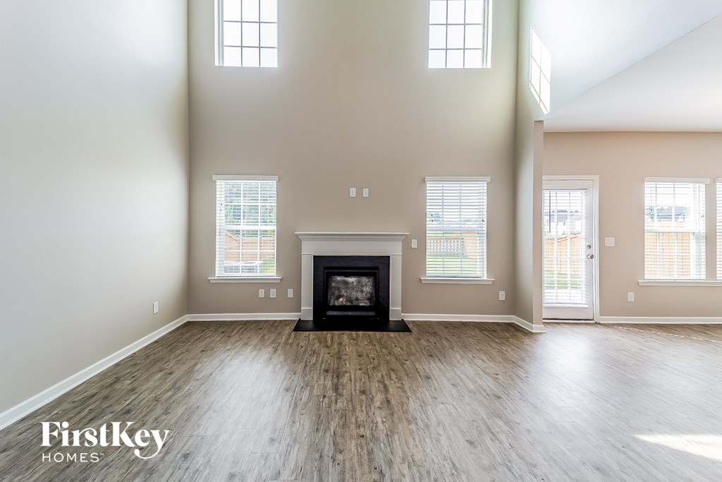 an empty living room with a fireplace and wooden floors