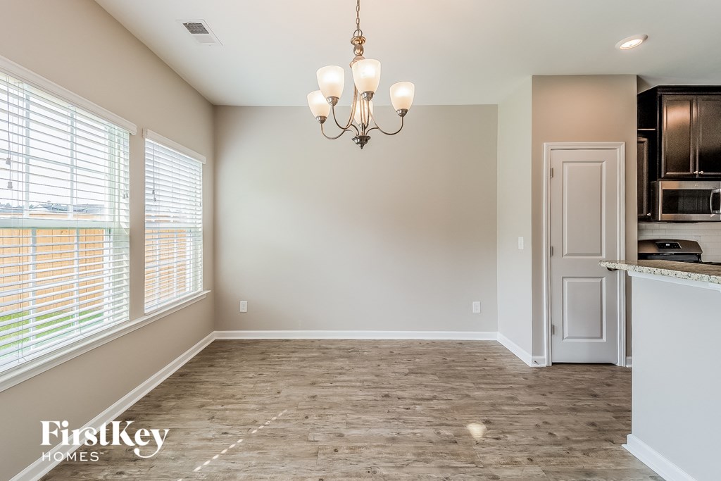 an empty dining room with a door to the kitchen