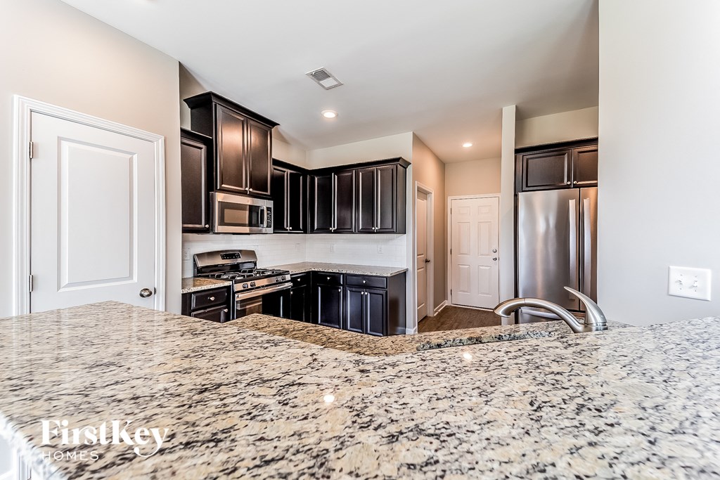 a kitchen with black cabinets and stainless steel appliances and granite counter tops