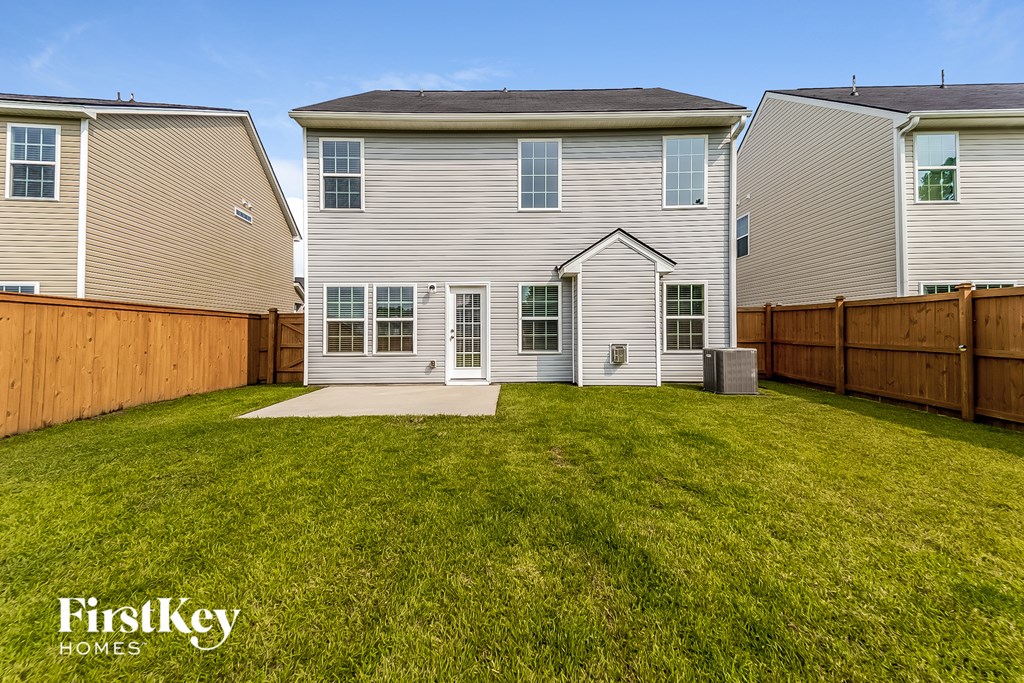 a backyard with a white house and a wooden fence