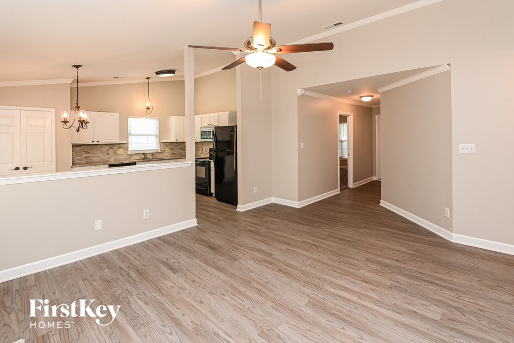 the living room and kitchen of an empty house with a ceiling fan