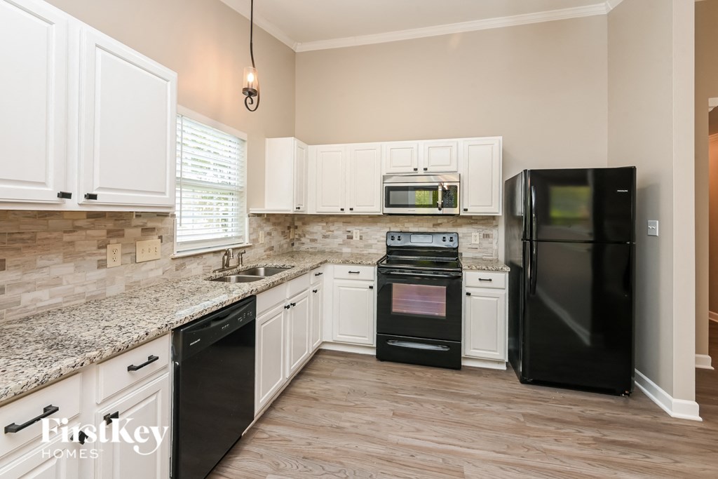 a kitchen with white cabinets and black appliances