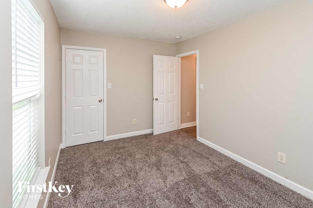 a bedroom with two doors and a carpeted floor