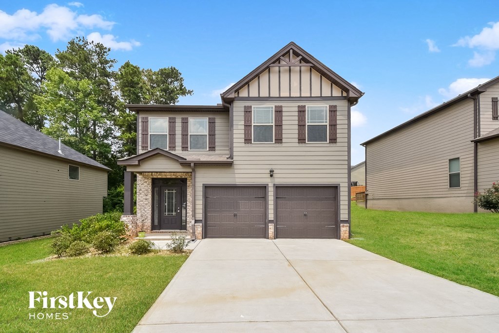 a beige house with two garage doors and a driveway