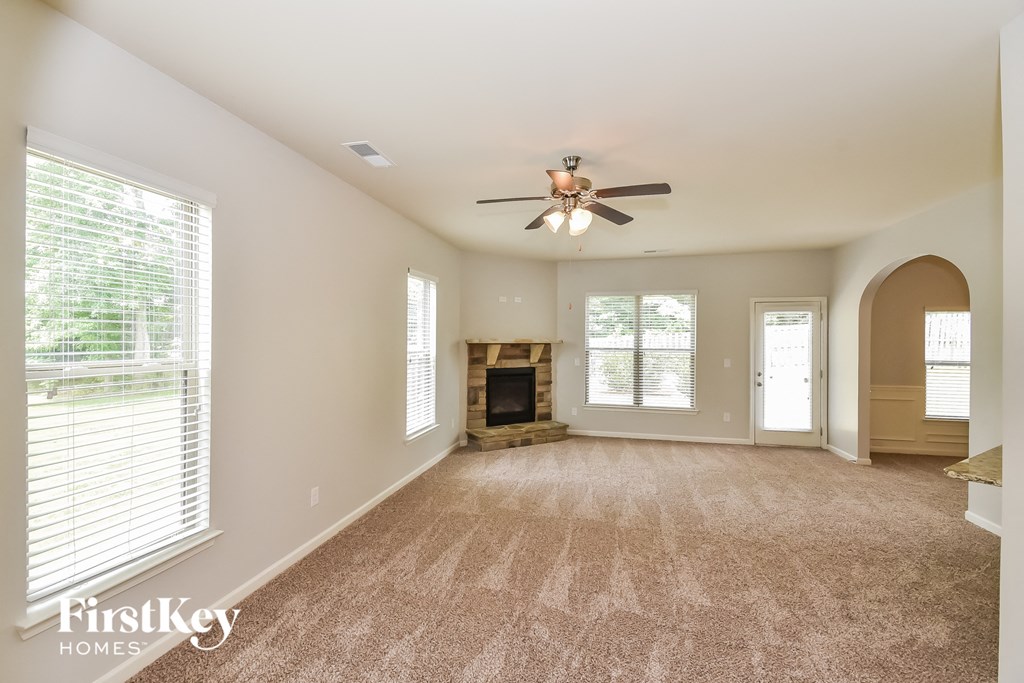 an empty living room with a ceiling fan and a fireplace